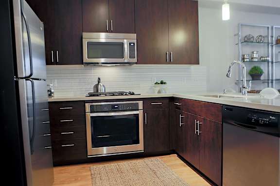 A modern kitchen with dark wood cabinets and stainless steel appliances.