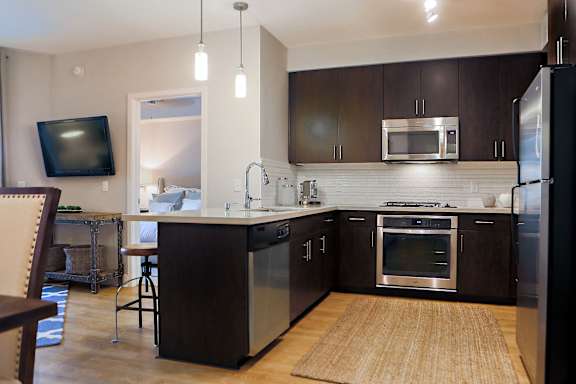 A modern kitchen with dark wood cabinets and stainless steel appliances.