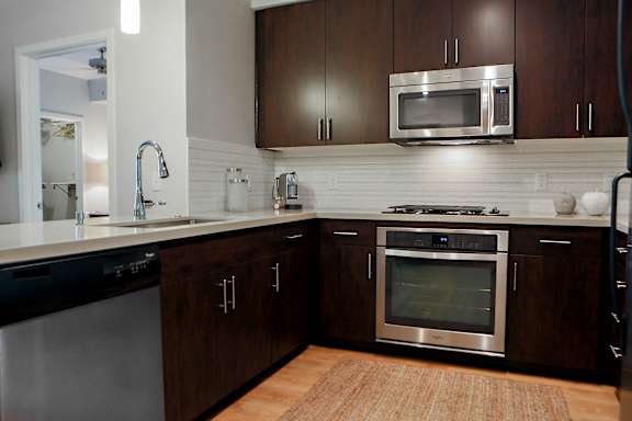 A modern kitchen with dark wood cabinets and stainless steel appliances.