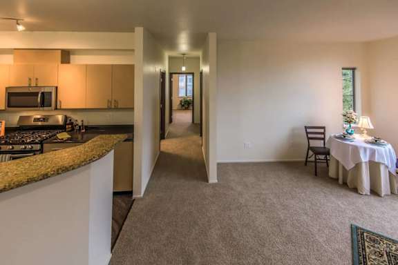 A kitchen with a table set for two in the living room.