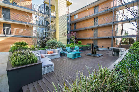 a patio with furniture and a fire pit in front of an apartment building
