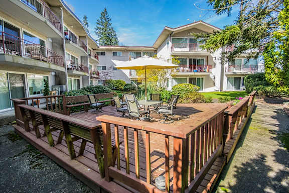 a wooden deck with a table and chairs and an umbrella