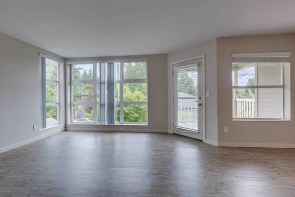 an empty living room with large windows and wood floors