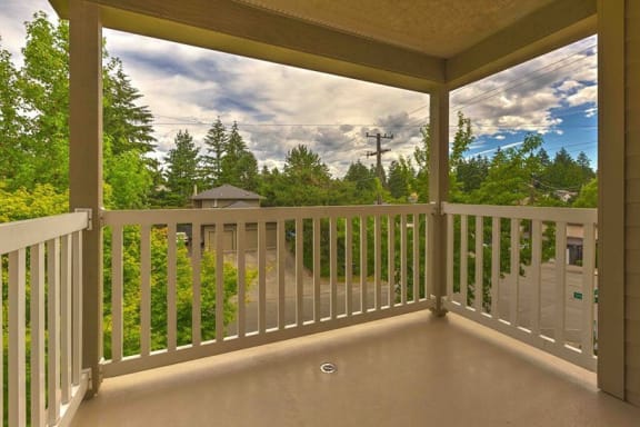 a balcony with a view of trees and a cloudy sky