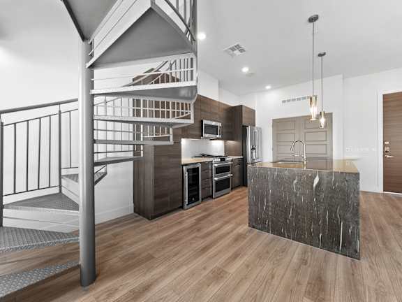 A modern kitchen with a wooden floor and a staircase.