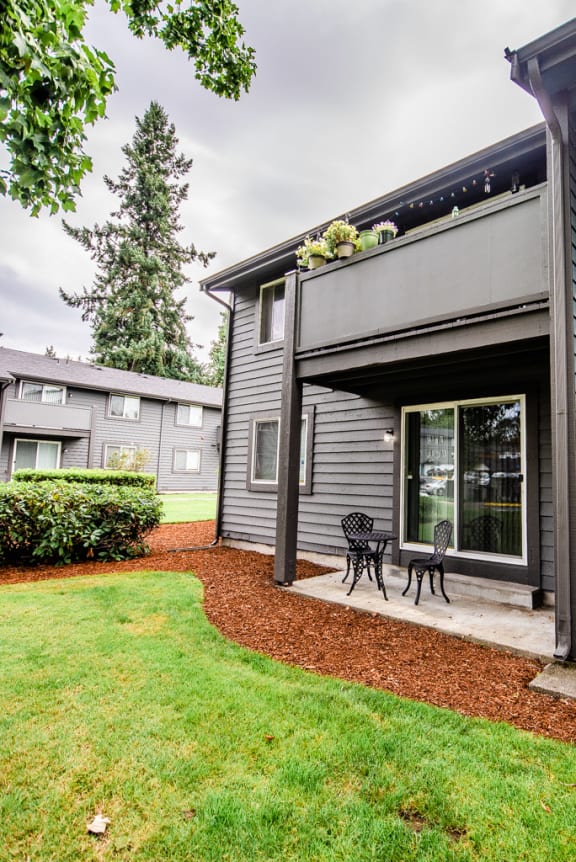 the back of a gray house with a patio with two chairs at Aero Apartments, Tacoma, WA, 98444