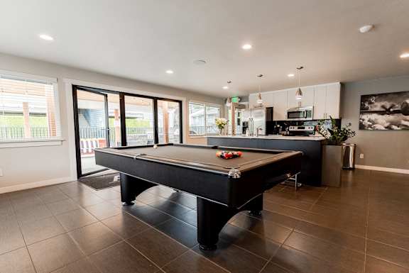 a pool table in a living room with a kitchen at Aero Apartments, Tacoma