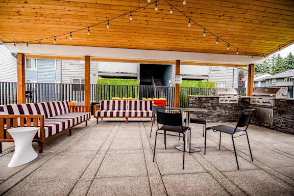 a covered patio with chairs and tables and a grill at Aero Apartments, Tacoma, Washington