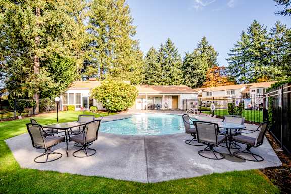 a swimming pool with patio furniture in front of a house