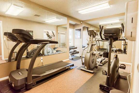 a gym with cardio machines and weights on the floor