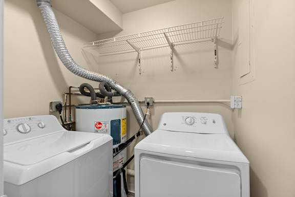 two washers and a dryer in a laundry room with a rack on top