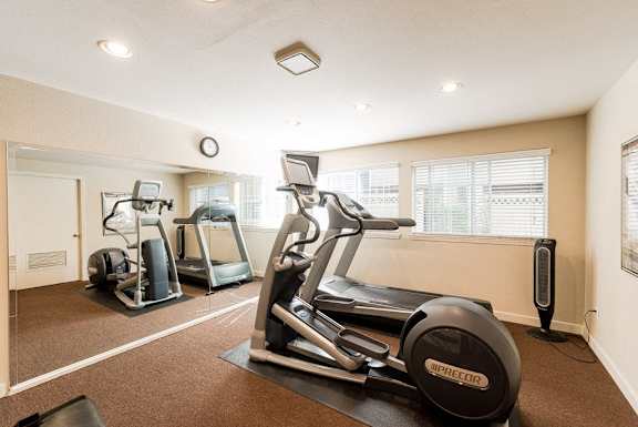 a gym with two treadmills and other exercise equipment at Cambridge on Seventh, Washington