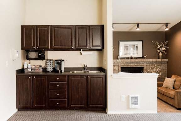 a kitchen with dark cabinets and a living room with a fireplace at Cambridge on Seventh, Washington, 98372