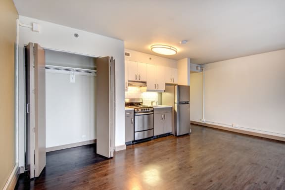 an empty living room and kitchen with a wood floor and white cabinets&#xA0;at Cosmopolitan, Seattle, WA