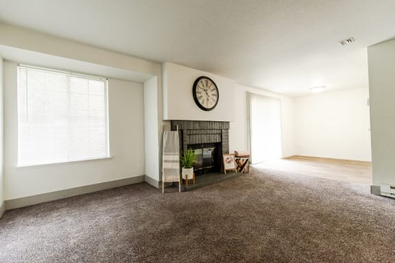 an empty living room with a fireplace and a clock on the wall