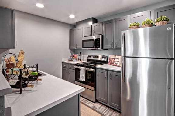 a kitchen with stainless steel appliances and gray cabinets at Deer Creek Apartments, Washington