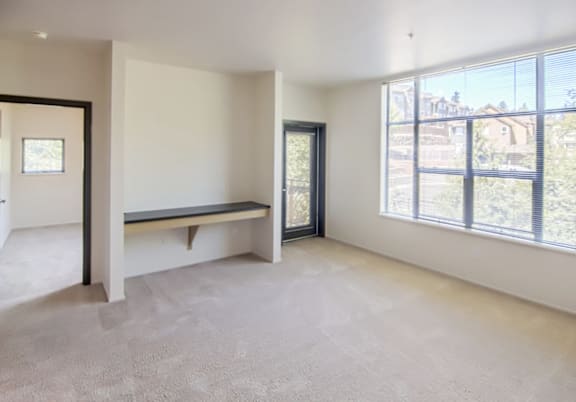 A room with a bench and a window overlooking a fence.