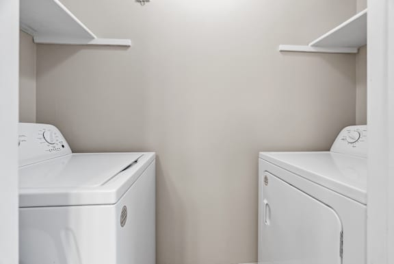 Two white front loading washing machines in a laundry room.