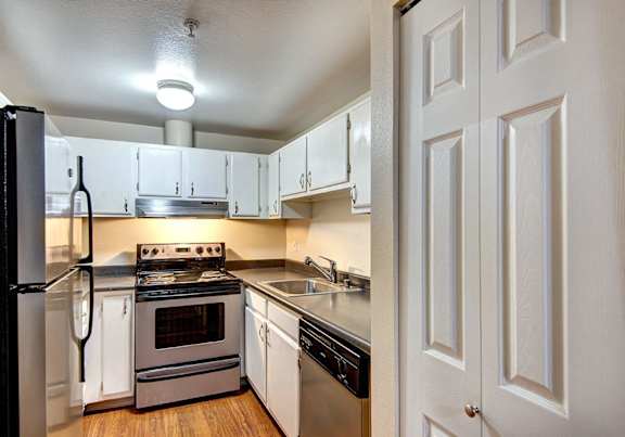 an empty kitchen with white cabinets and stainless steel appliances at Ellis Court Apartments, Seattle, 98121