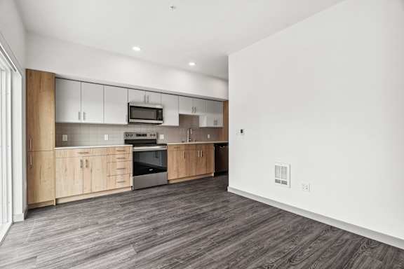 A modern kitchen with wooden floors and cabinets.