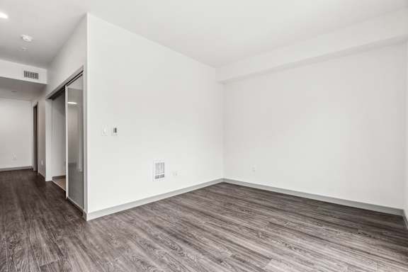 A room with a white wall and wood flooring.