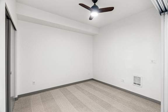 A room with a ceiling fan and carpeted floor.