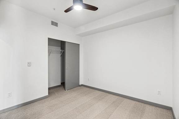 A room with a ceiling fan and a closet.