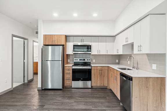 A modern kitchen with a stainless steel refrigerator, oven, and sink.
