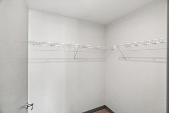 A white closet with two shelves and a door.