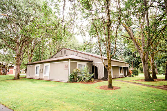 a house with a yard and trees in front of it