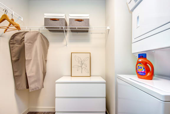 a small laundry room with a washer and dryer and a shelf with baskets
