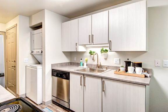 an apartment kitchen with stainless steel appliances and white cabinets