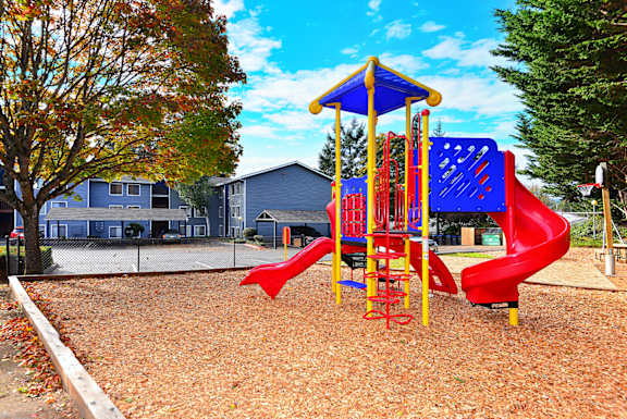 a playground with a red slide and blue and yellow structure