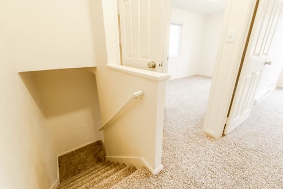 an empty hallway with a staircase with a white railing and a door at Pacific Walk, Lakewood, WA