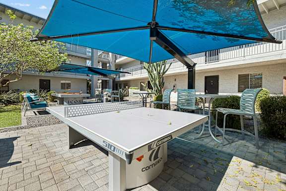 A table tennis table with a blue umbrella above it.