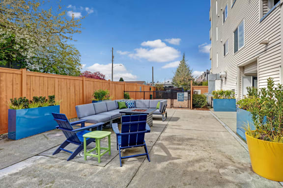 a patio with blue chairs and a table and a blue fence