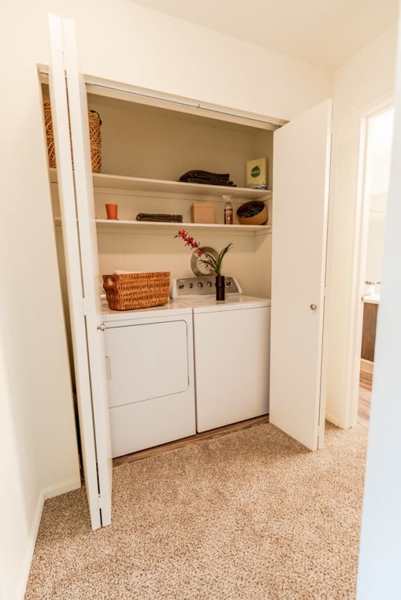 a small laundry room with white appliances and shelves