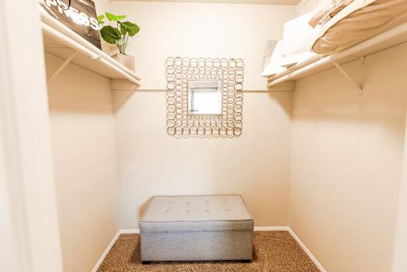 A small room with a square mirror and a bench.