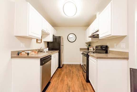 A kitchen with white cabinets and black appliances.