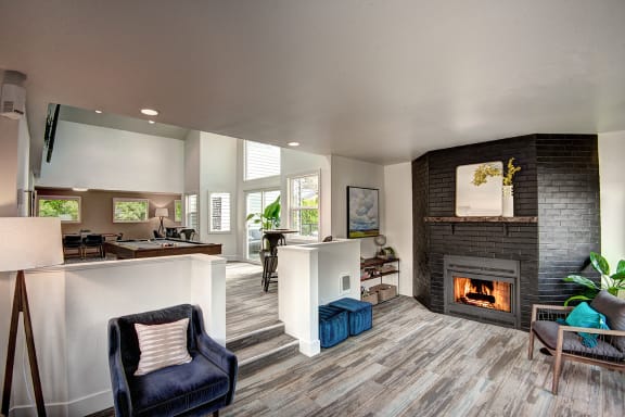a living room with a fireplace and a kitchen at The Lynx Apartments, Everett, 98204