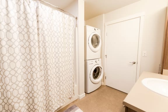 a washer and dryer in a laundry room with a shower and a sink
