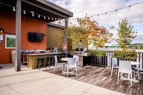 A patio with a table and chairs and a TV on the wall. at The Platform, Kent, WA, 98032