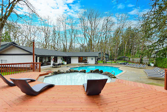 a backyard with a pool and a deck with chairs