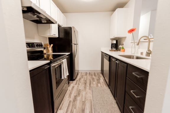 a kitchen with black appliances and wooden floors at Vibe, Kent, 98030