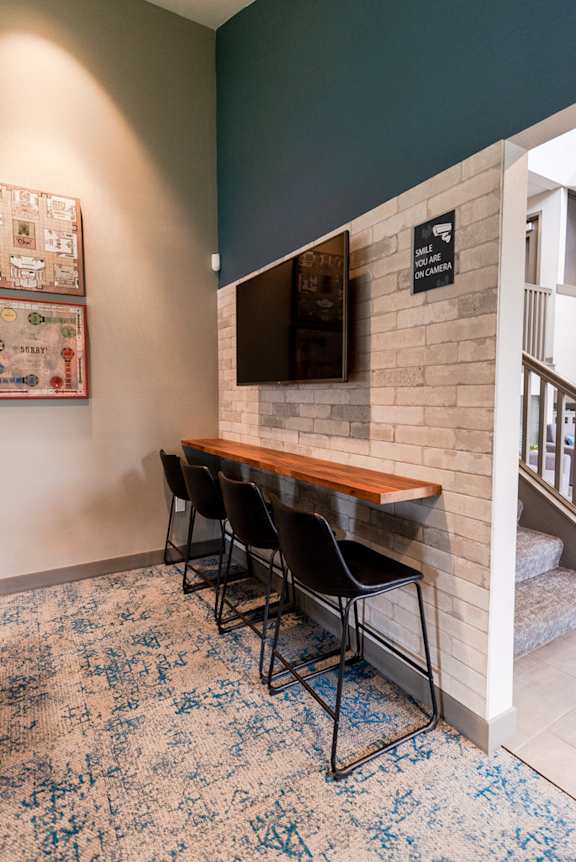 a bar with black chairs and a white brick wall with a television at Vibe, Washington, 98030