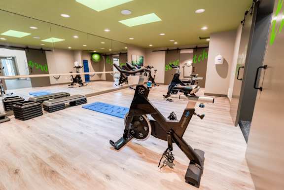 a gym with exercise machines and weights on a wooden floor at Vibe, Kent, Washington