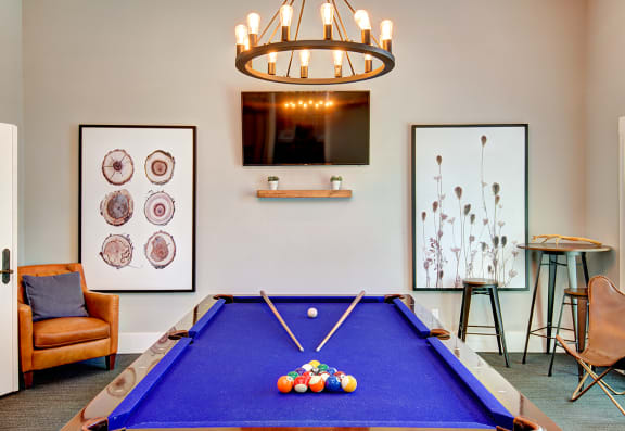a games room with a blue pool table and a tv at Deer Creek Apartments, Puyallup, 98373