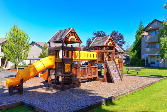 a playground with a swing set and a slide at Deer Creek Apartments, Puyallup