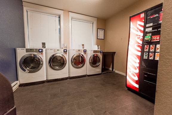 a laundry room with four washing machines and a coca cola machine at Zindorf, Seattle, WA