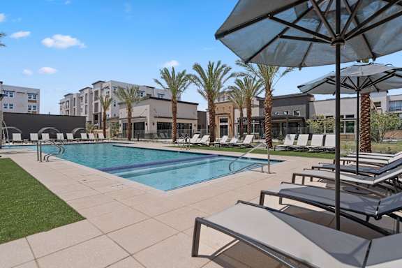 A pool surrounded by palm trees and lounge chairs.